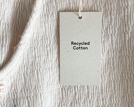 Recycled cotton fashion label tag, sale price card on luxury fabric background, shopping and retail