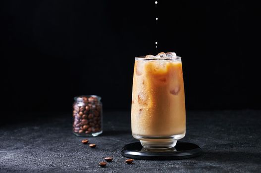 Cold Summer Drink. Iced Coffee with Milk Drops in Tall Glass on Dark Background. Drinks in Motion. Copy Spase
