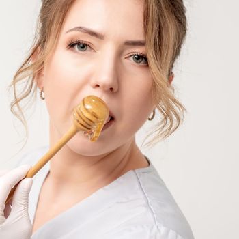Woman eating honey with wooden spoon
