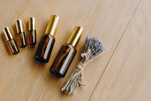 Essential oil in one bottle and dried lavender standing on the surface