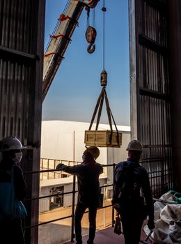 The crane carrying a wooden box of radioactive instrument holder to the high floor of the plant