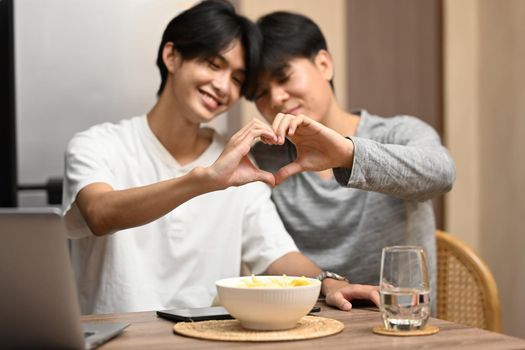 Young homosexual couple making heart with their hands. LGBT, pride, relationships and equality concept