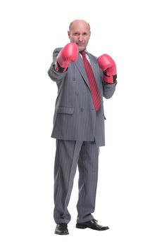 Serious caucasian elderly man in business formal outfit in boxing gloves hitting