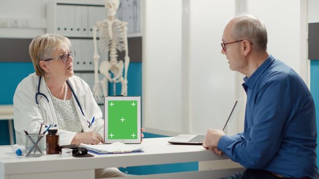 Doctor showing tablet with greenscreen to retired patient