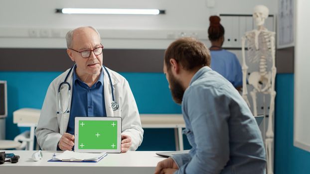 Physician holding digital tablet with horizontal greenscreen