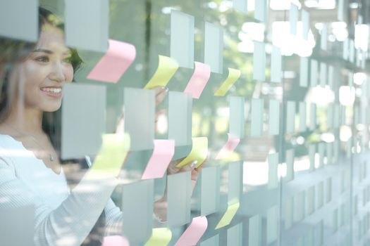 businesswoman woman thinking planning with adhesive notes on glass wall