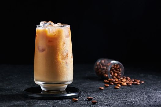 Iced Coffee with Milk in Tall Glass on Dark Background. Concept Refreshing Summer Drink