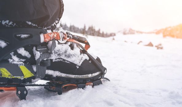 Foot with crampon standing on snow