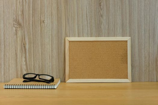 cork board notebook glasses on wooden table at office