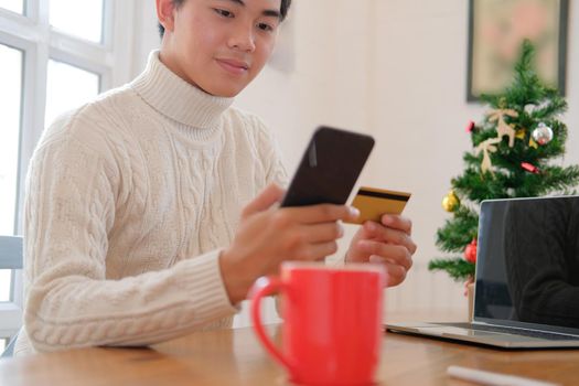 man holding credit card & smart phone for online shopping.  male buyer buying christmas gift on internet. xmas new year holiday celebration