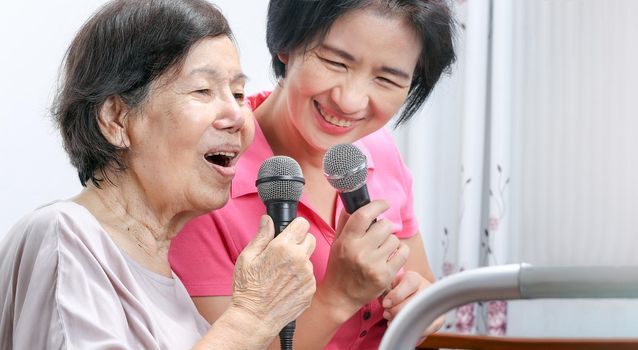 Elderly woman sing a song with daughter at home.