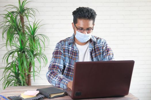 Businessman in face mask working on laptop