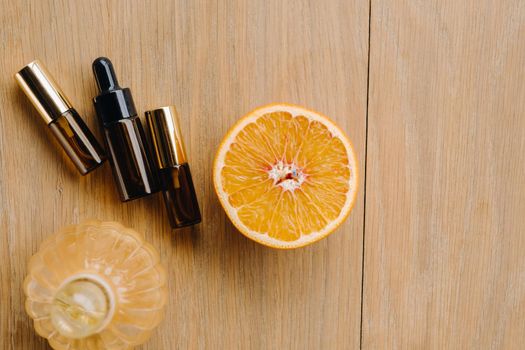 Essential oil in one bottle and orange slices lying on the surface