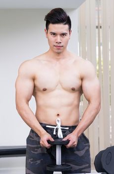 Muscular man bodybuilder training with dumbbells.