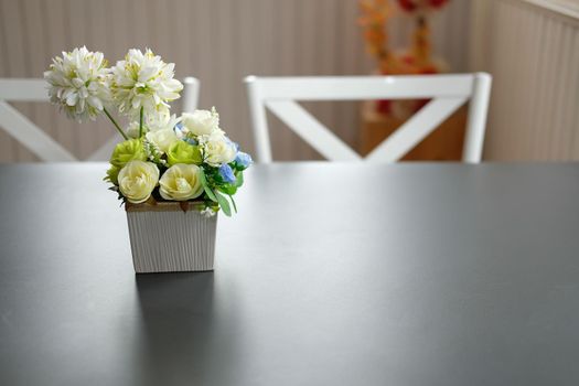 artificial rose on black table. white chair set in cozy dining room interior