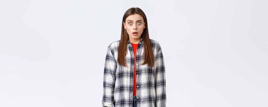 Lifestyle, different emotions, leisure activities concept. Shocked and scared, startled young woman in checked casual shirt, staring terrified, see something scary, standing in stupor
