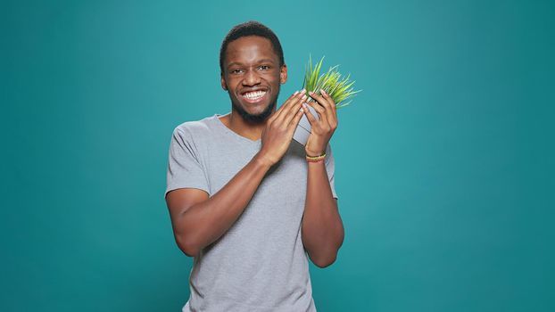 Cheerful person holding pot with houseplant in studio