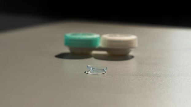 Contact lenses and a storage container on a white table.