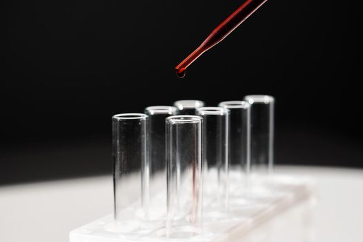 Close-up of a laboratory assistant dripping blood from a pipette into a test tube.
