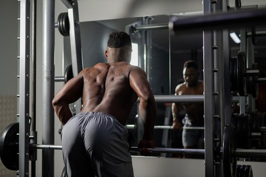 Handsome afro american man posing showing back muscles in gym.