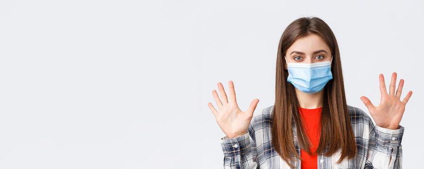 Coronavirus outbreak, leisure on quarantine, social distancing and emotions concept. Attractive caucasian woman in medical mask show ten fingers, amount or quantity, white background