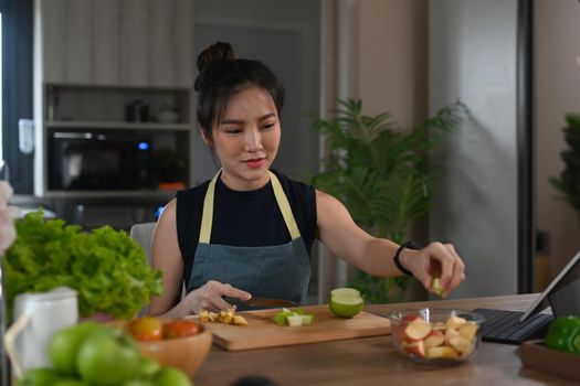 Young vegetarian woman preparing healthy salad in kitchen. Healthy lifestyle concept.