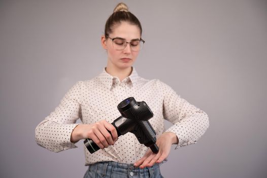Caucasian business woman massaging her wrist with a percussion massager.