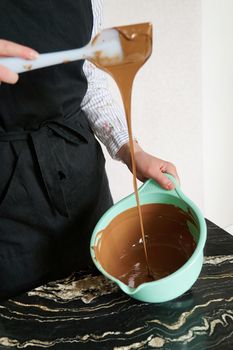 Closeup - confectioner - woman stirs chocolate for making homemade chocolates