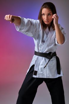 Athletic woman in traditional kimono is practicing karate in studio.