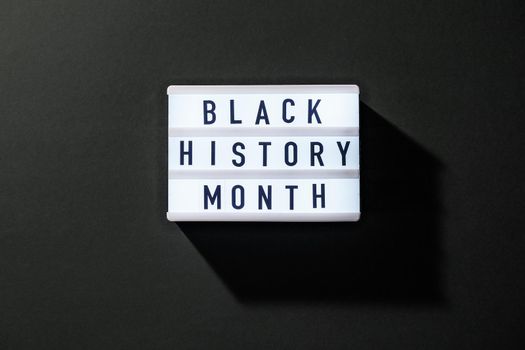 Lightbox with text BLACK HISTORY MONTH on dark black background. Message historical event.