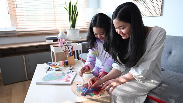 Happy adorable siblings enjoy painting pictures together in living room.