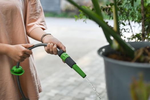 Female watering plants in the garden with hose. Gardening, hobby, domestic life concept.