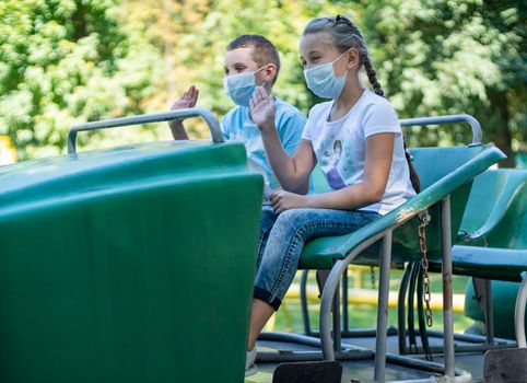 children in medical masks ride the attraction