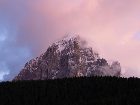 Langkofel during Sundown seen from La Selva in Val Gardena. The Sassolungo, Lang Kofel covered in Snow in Spring with clouds covering the Peak of the Sasso Lungo