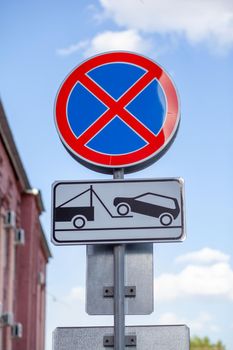 The road sign prohibits stopping against the background of buildings and cars. Close-up road signs No stopping and Tow Away Zone in city. Road signs of Stopping is prohibited