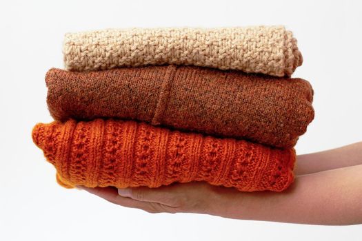 Hands holding stack with woolen clothes