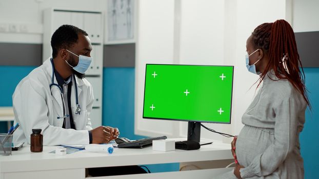 Medic and expectant patient looking at computer with greenscreen