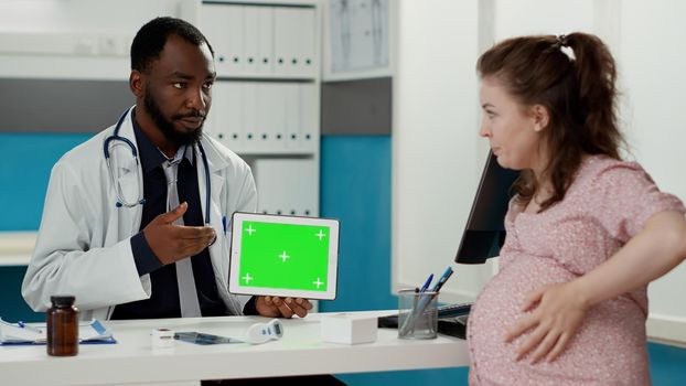 Obstetrician working with horizontal greenscreen on tablet