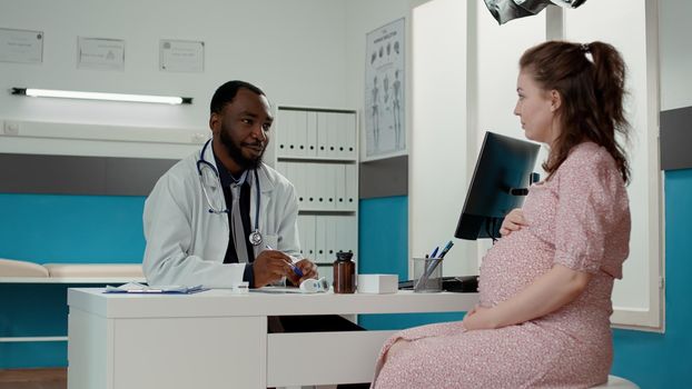 General practitioner consulting woman expecting child in office