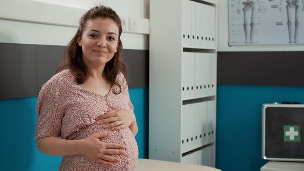 Portrait of pregnant patient waiting for doctor to attend physical examination