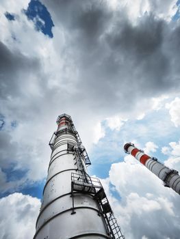 White chimneys of a power plant on a background of clouds with diagonal lines