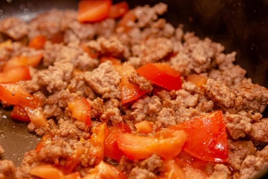 Bolognese ragout in a frying pan with wooden spoon, authentic recipe, close-up