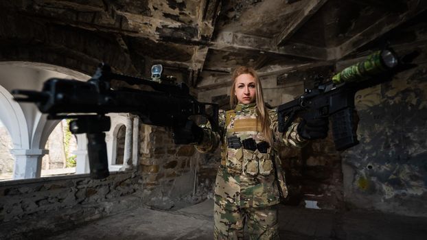 Caucasian woman in army uniform holding two machine guns.