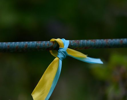 blue and yellow silk ribbon tied on a metal tube. Ukrainian flag symbol, struggle for independence