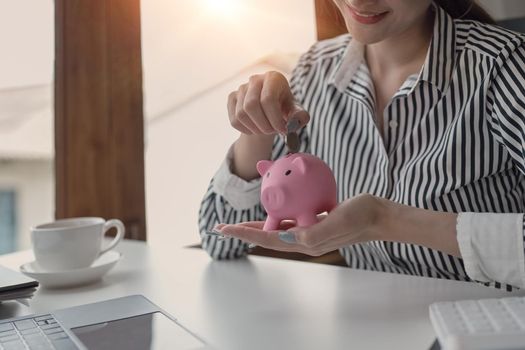 Woman hand putting coin into piggy bank. Saving money for future, retirement fund, business investment, finance concept.