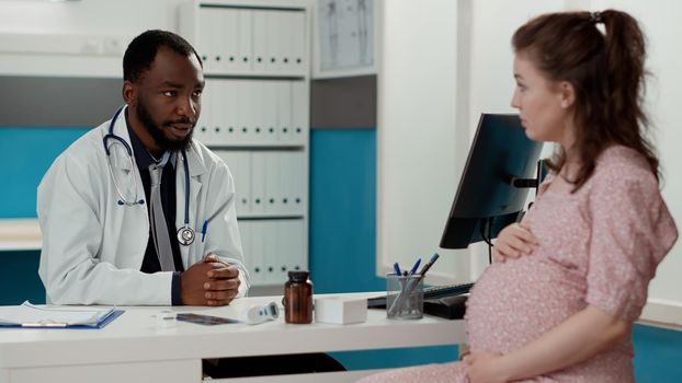 General practitioner having conversation with pregnant patient