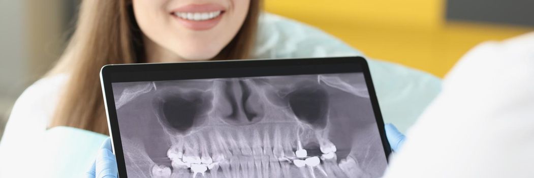 Dental consultation in clinic and doctor examine teeth x ray on digital tablet screen