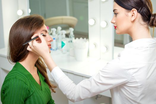 Makeup artist applies eyeshadow.