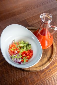 Tasty appetizing summer tomato soup puree gazpacho with tomatoes and cucumbers served in bowl