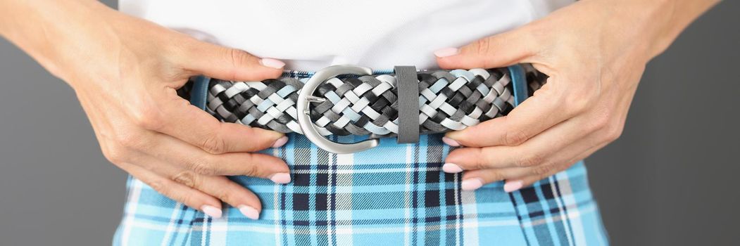 Woman touching new trendy belt wearing with plaid printed skirt